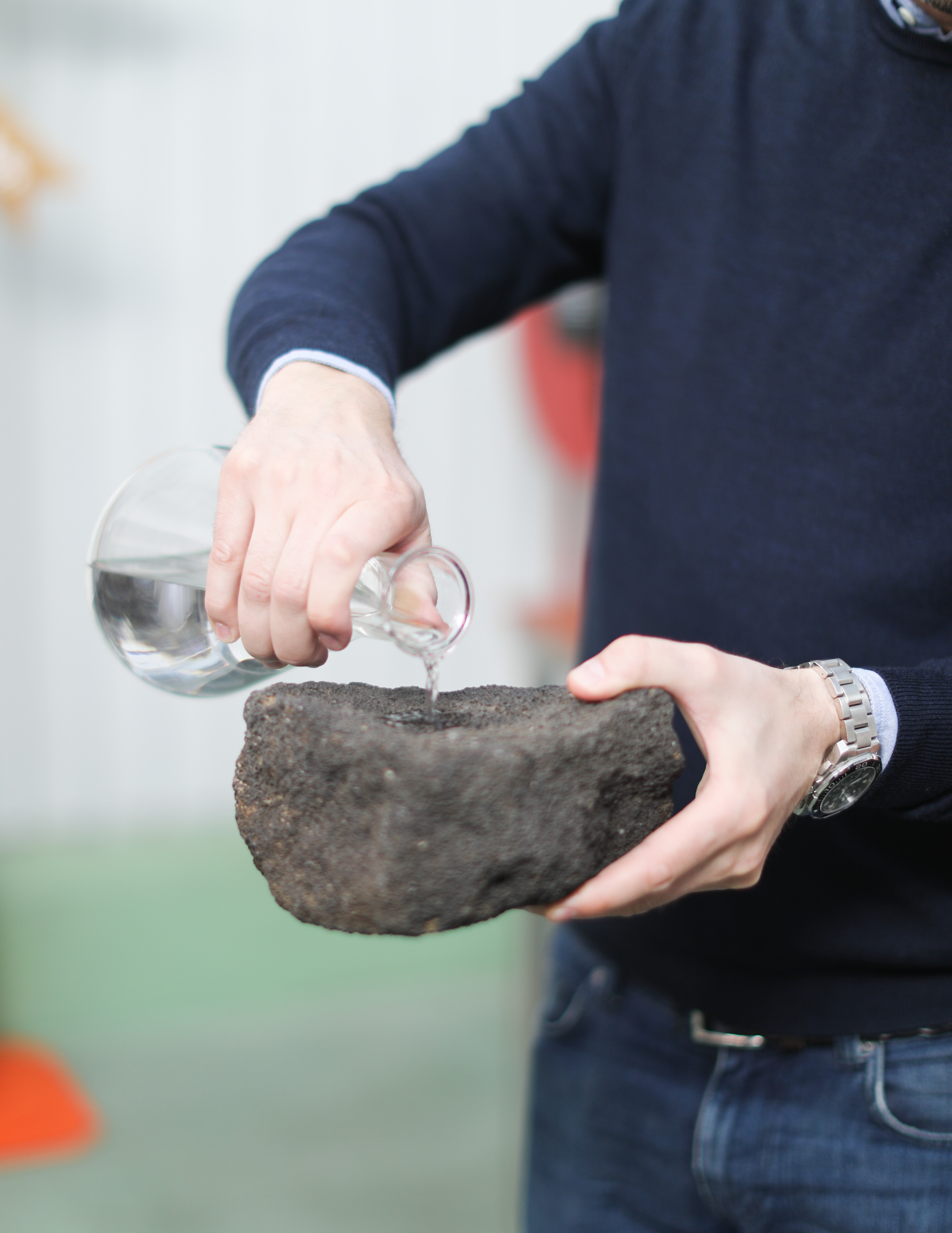 Distiller pours vodka into a piece of charcoal to demonstrate pure distillation process.