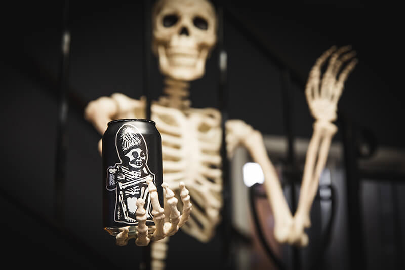 Skeleton holding a Rogue Dead Guy Ale can.