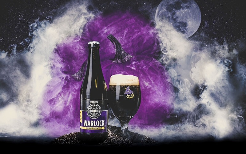 Southern Tier Warlock bottle with purple pumpkins surrounded by smoke in the background.